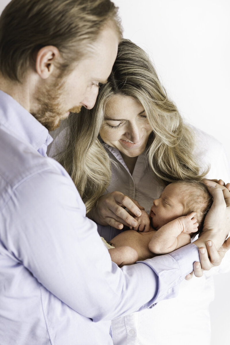 New parents lovingly look at their newborn son during their in-home session