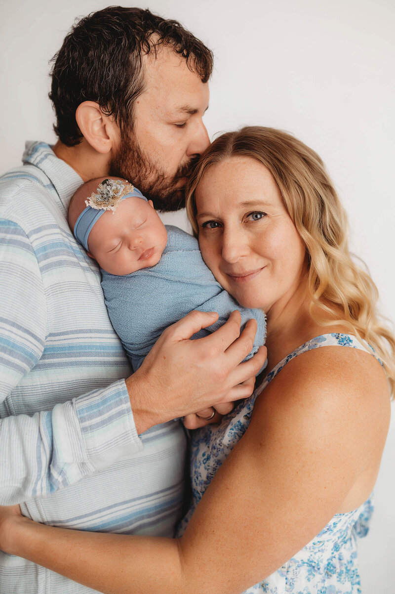 New parents embrace their infant during Newborn Photoshoot in Charleston, SC.