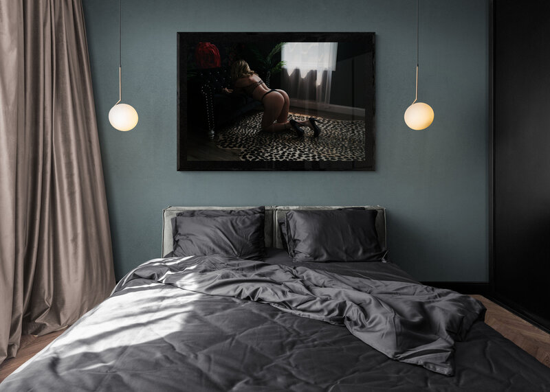 Luxury artwork of  A woman on her knees leans onto a couch in black lingerie and high heels hangs on a wall above a grey bed