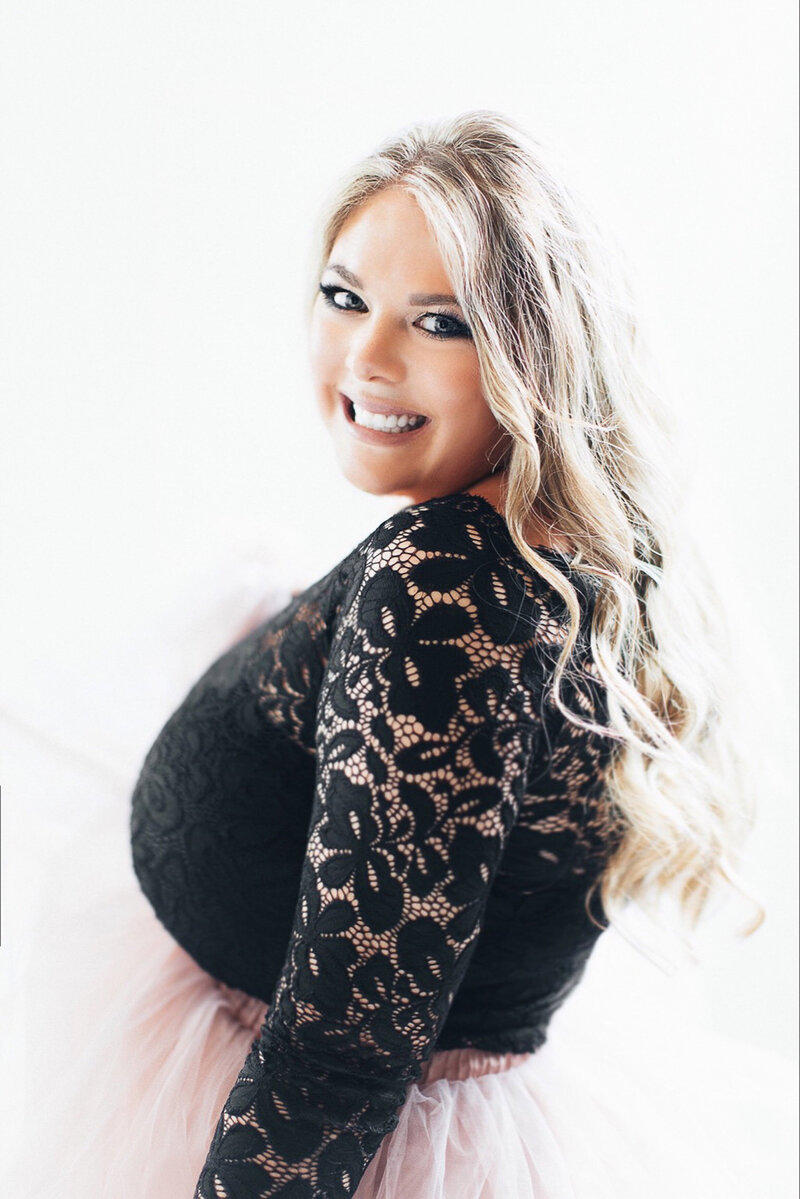 Liza Nicole, top Philadelphia family newborn and maternity photographer is standing side profile to the camera and looking over her should and smiling.