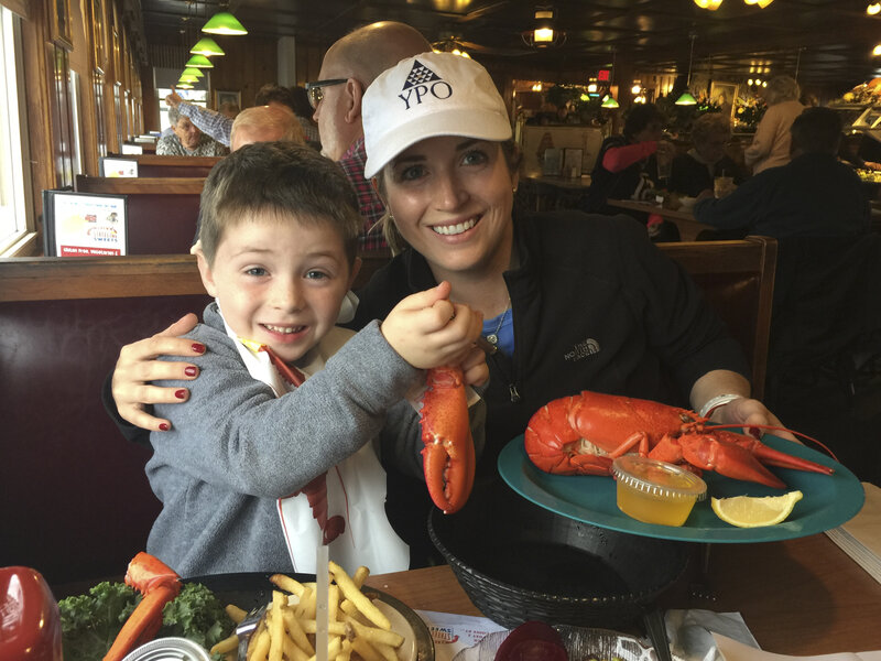 a mother and child eat lobster in restaurant in maine. YPO Family Travel