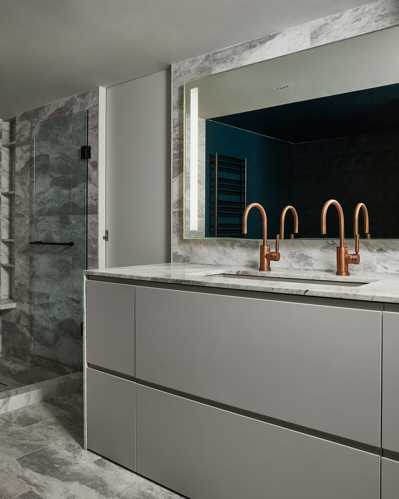 An elegant vanity area featuring a long concrete sink, bronze faucets, a marble countertop, and large mirror