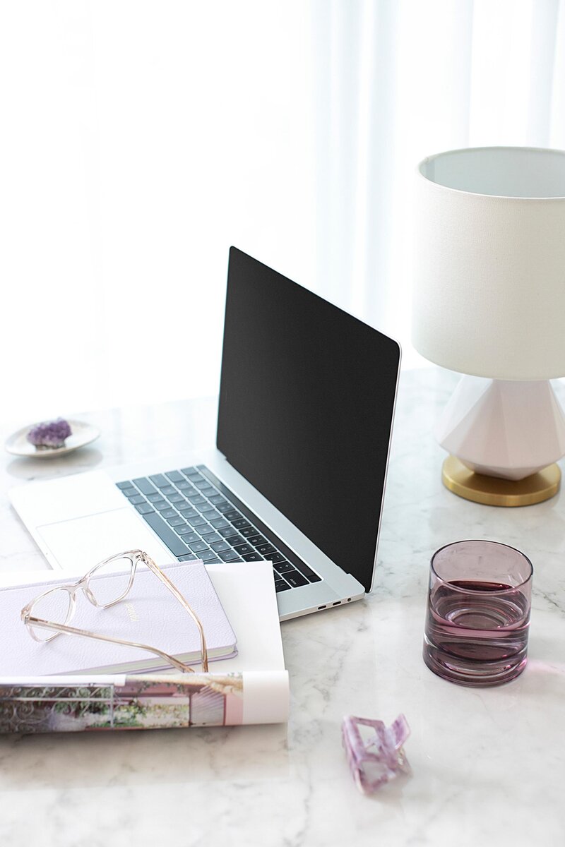 Laptop sobre la mesa, libros, gafas, agua  y cristal de ametista.