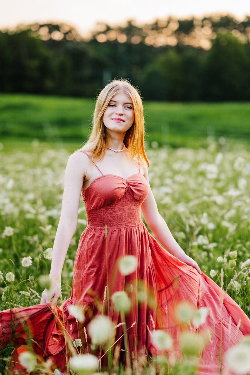 Girl standing in a white flower field for her senior pictures in Boston