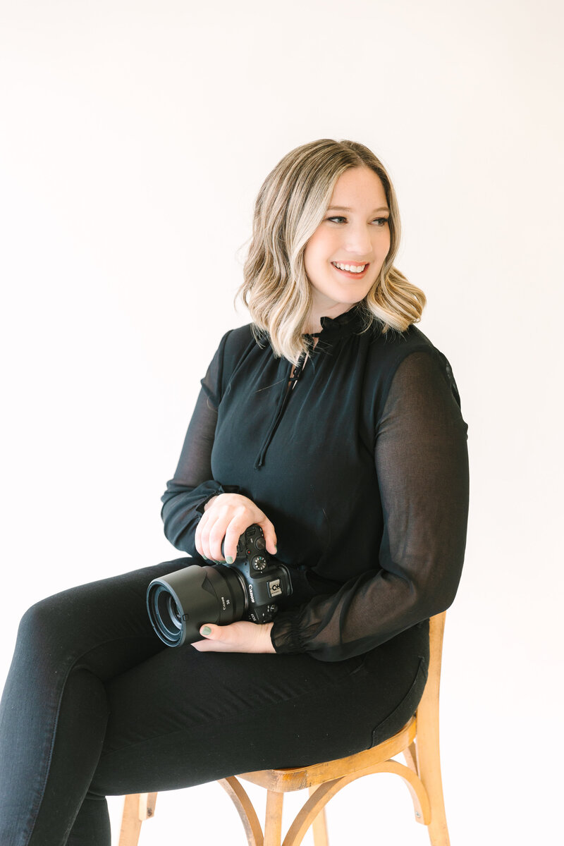 Amy Jordan Photography sitting in chair with camera in hand