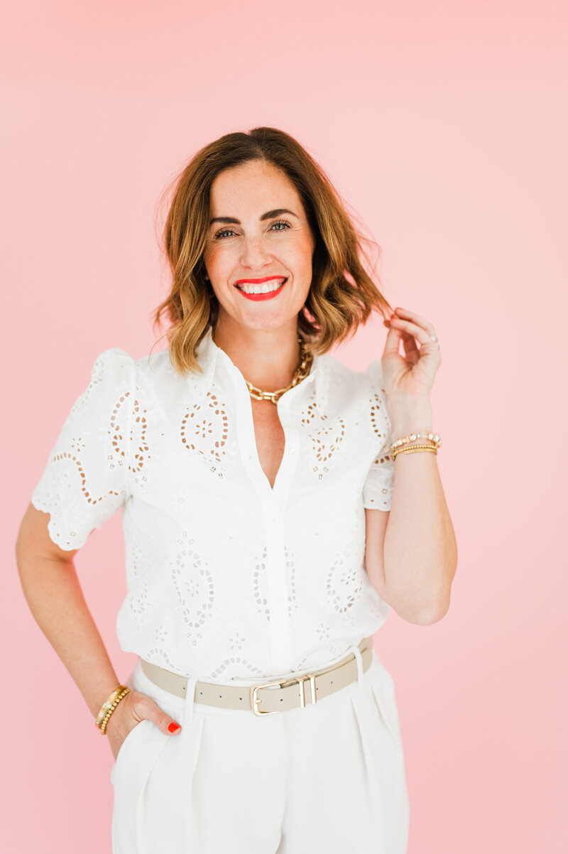 woman wearing white and standing in front of pink wall