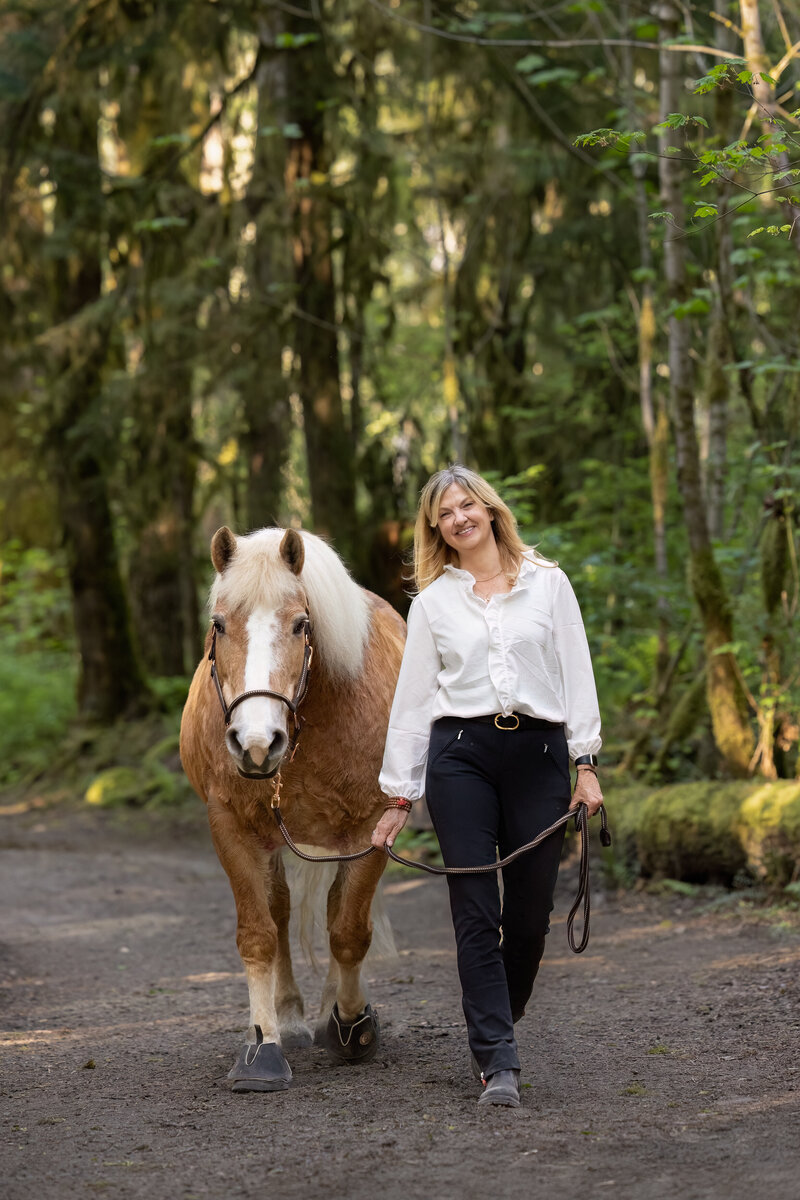 woman and horse walking side by side down path 