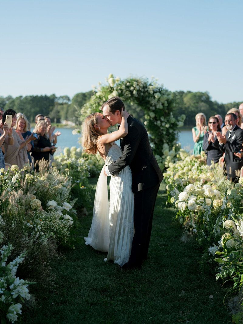 Bride and groom sharing a kiss as they walk down the aisle together after wedding ceremony