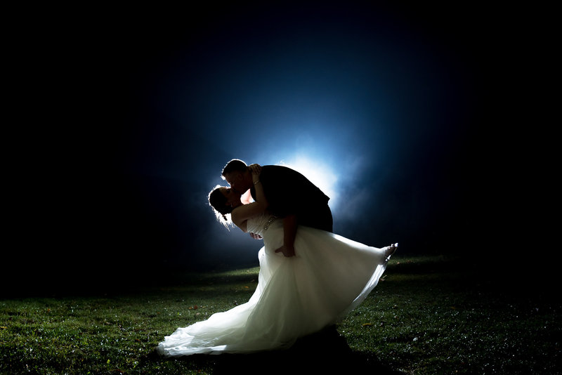 Couple backlit in blue as they dip for a kiss