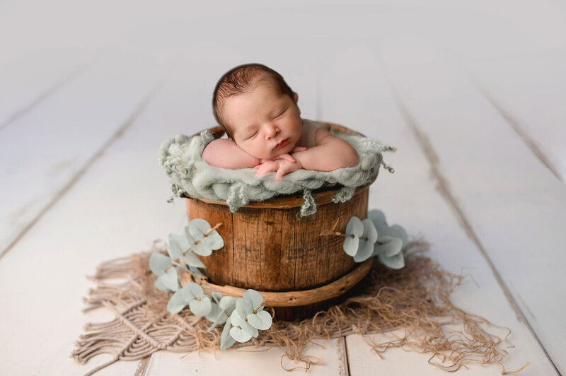 baby boy in a wooden basket on a white backdrop