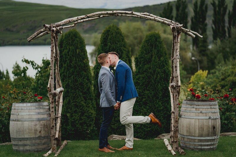groom and groom kissing under archway