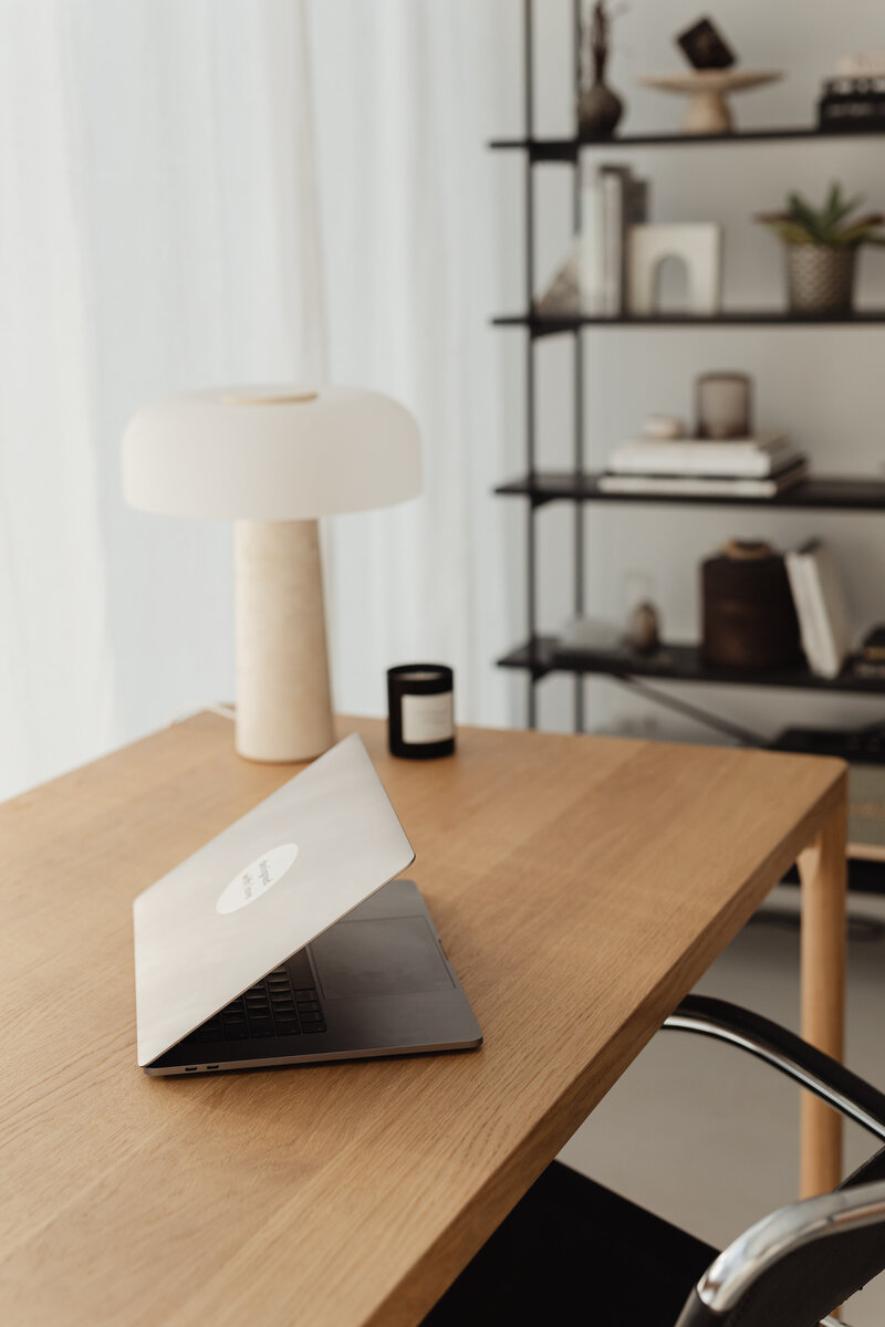 travertine lamp candle and laptop sitting on wood home office desk