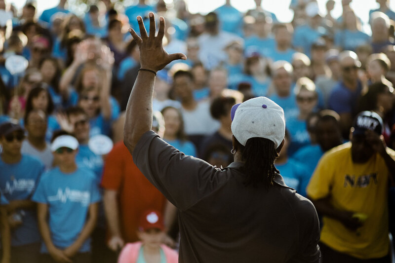 Chicago DJ leading a crowd at outdoor corporate event with attendees in branded shirts