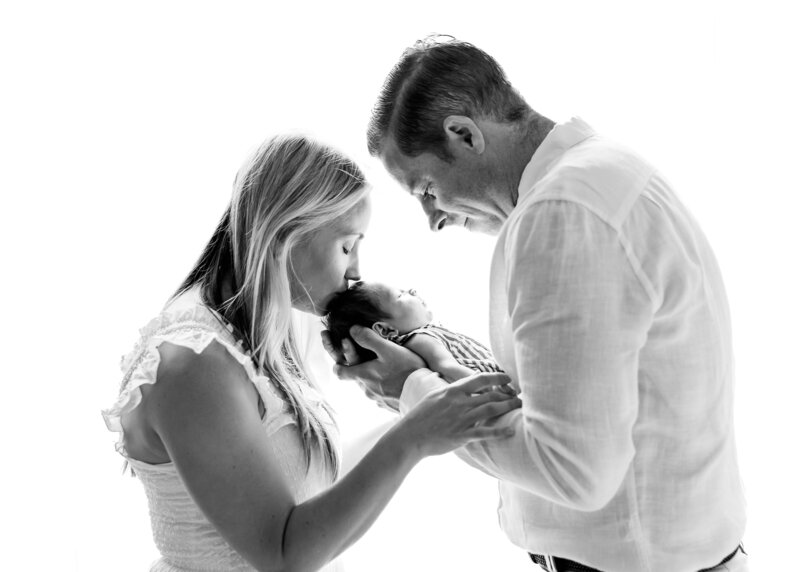 Mom and dad holding newborn baby in a lifestyle newborn photo session in their New Jersey home.