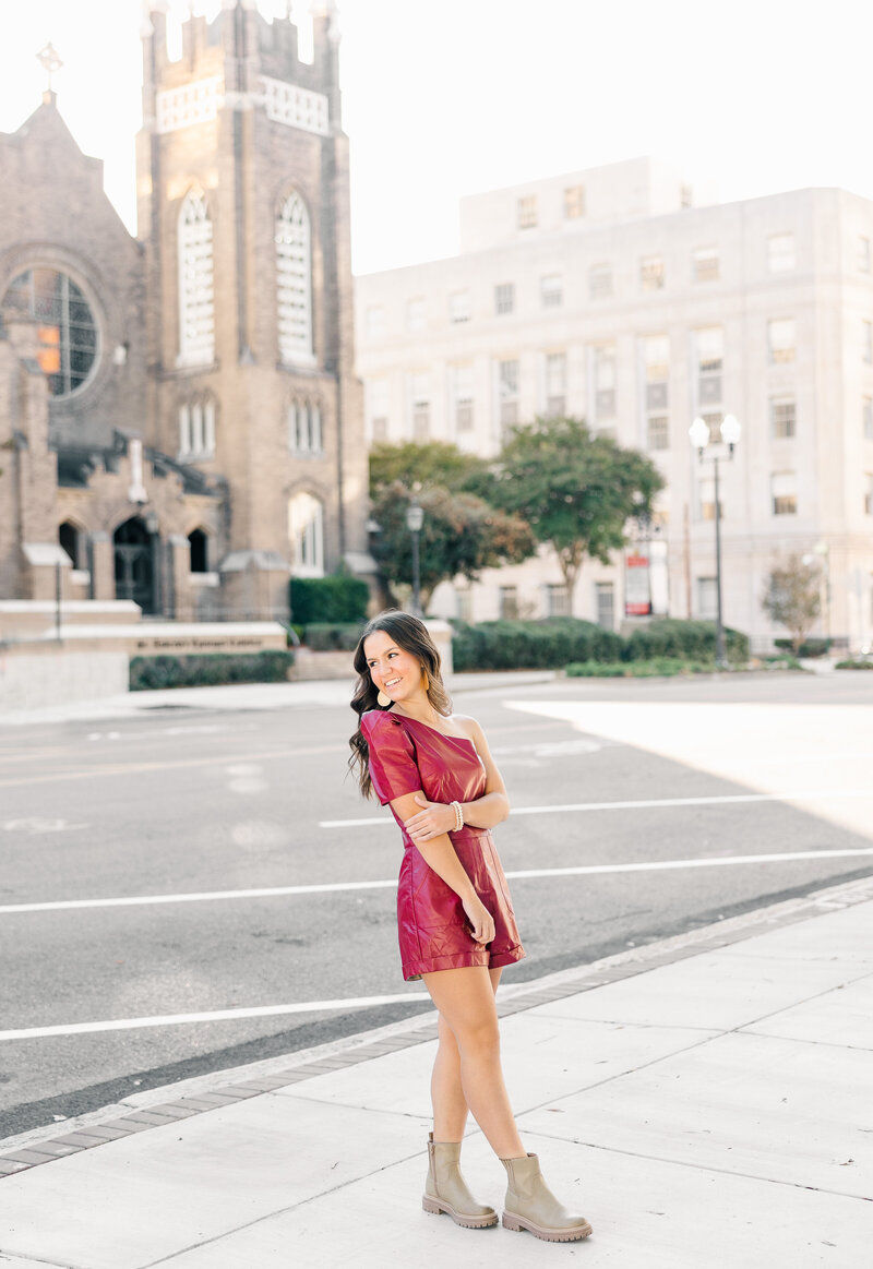 girl smiling in a red dress with the cityscape in the background