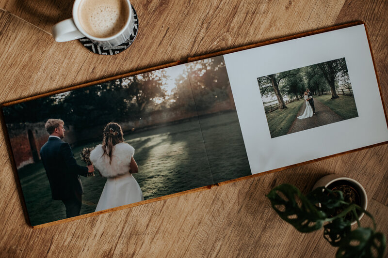 A top down shot of an open wedding album showing a spread with two wedding photos taken on grassy fields