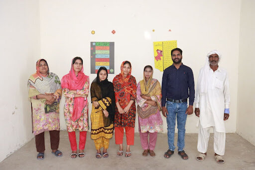 Paid on-site team stands in front of the school where they serve the children.