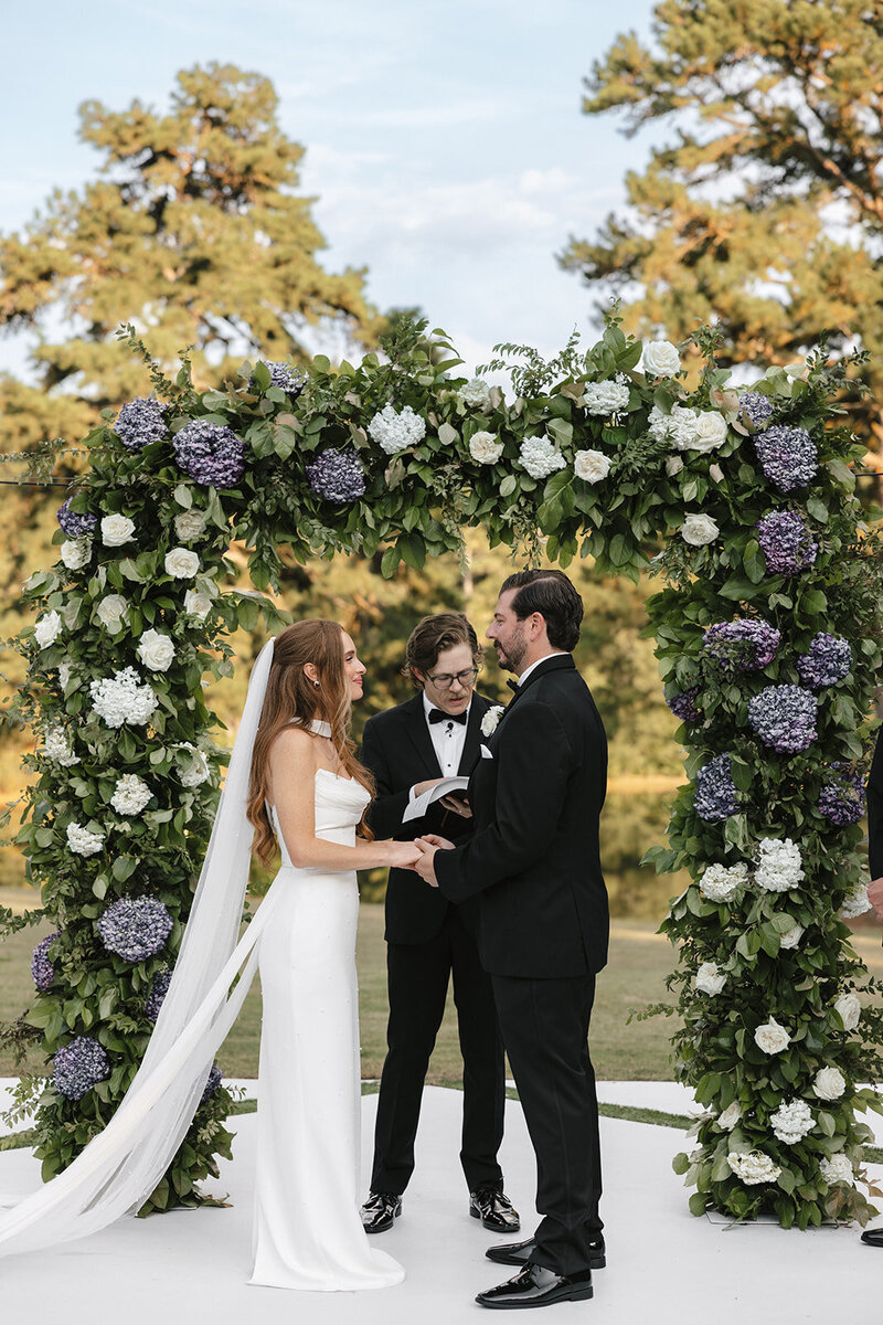 Vow exchange with floral arch at Atlanta wedding ceremony.