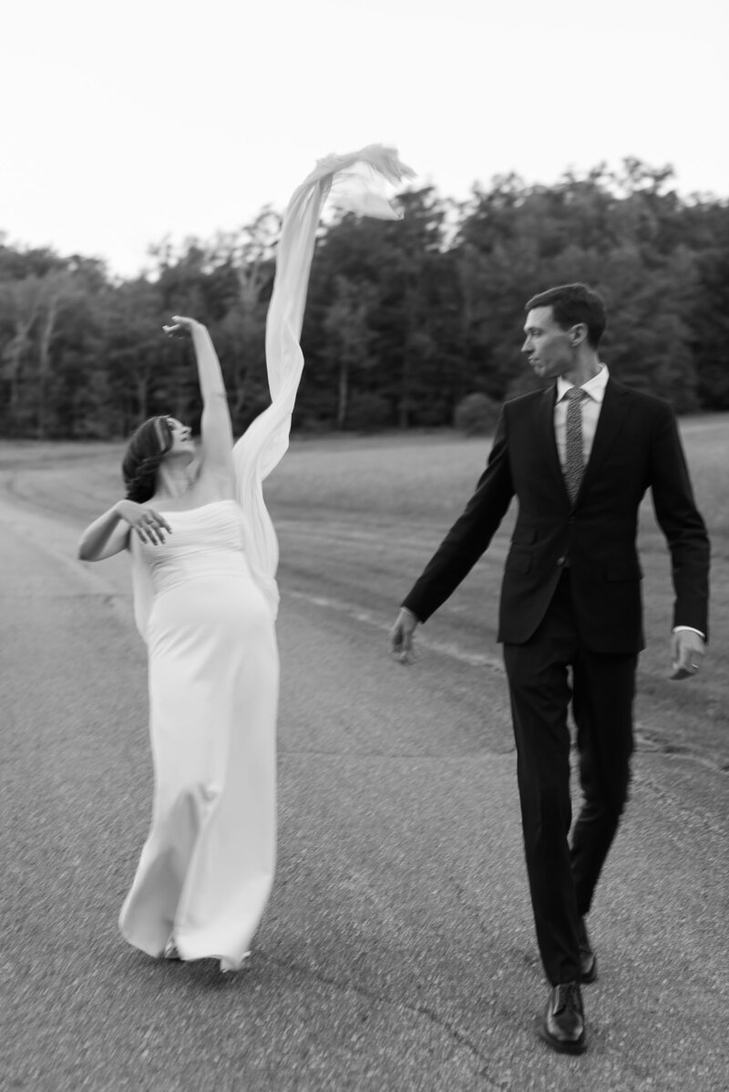 Bride tosses dress over her shoulder in black and white image