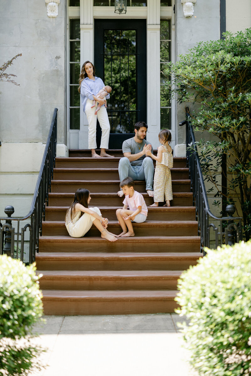 Family photography in Pearland Texas. Family of 6 standing in doorway outside with mom holding newborn. Captured by Amy Marie Photography. 