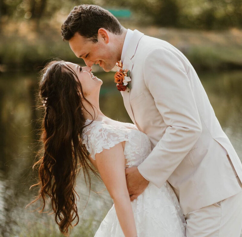A romantic dip shared between a bride and groom by a serene lake