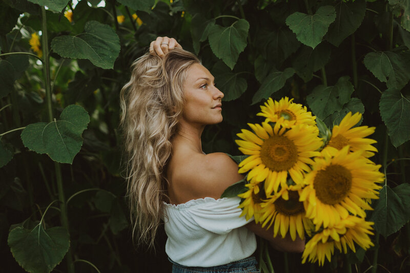 Portrait of a woman standing in a sunflower field holding sunflowers in her hand in Helsinki in Finland