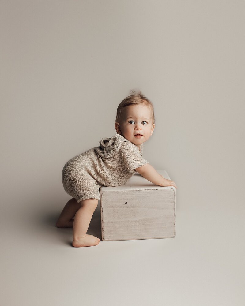 Baby waving to camera with big toothy smile during milestone session