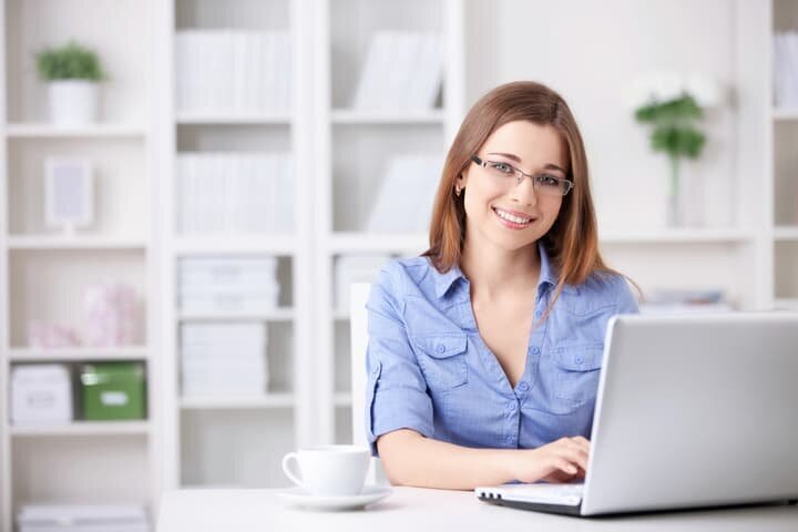 Freelance book editor smiling while working on laptop, offering editorial services for writers