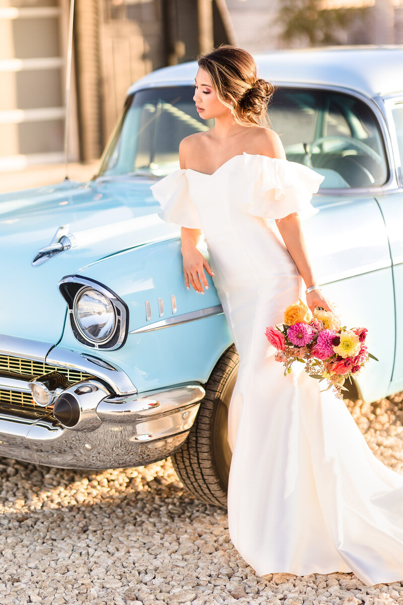 Bride poses with car outside the Camino Real Ranch wedding venue in Dale, Texas.