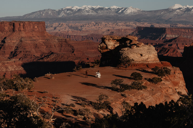 Wedding couple running across Shaffer Canyon Overlook at their elopement in Canyonlands National Park in Moab, Utah