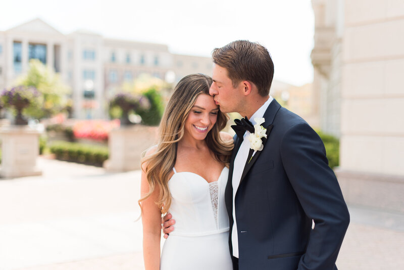 Groom kisses brides forehead and she looks down and smiles at their wedding in Indianapolis