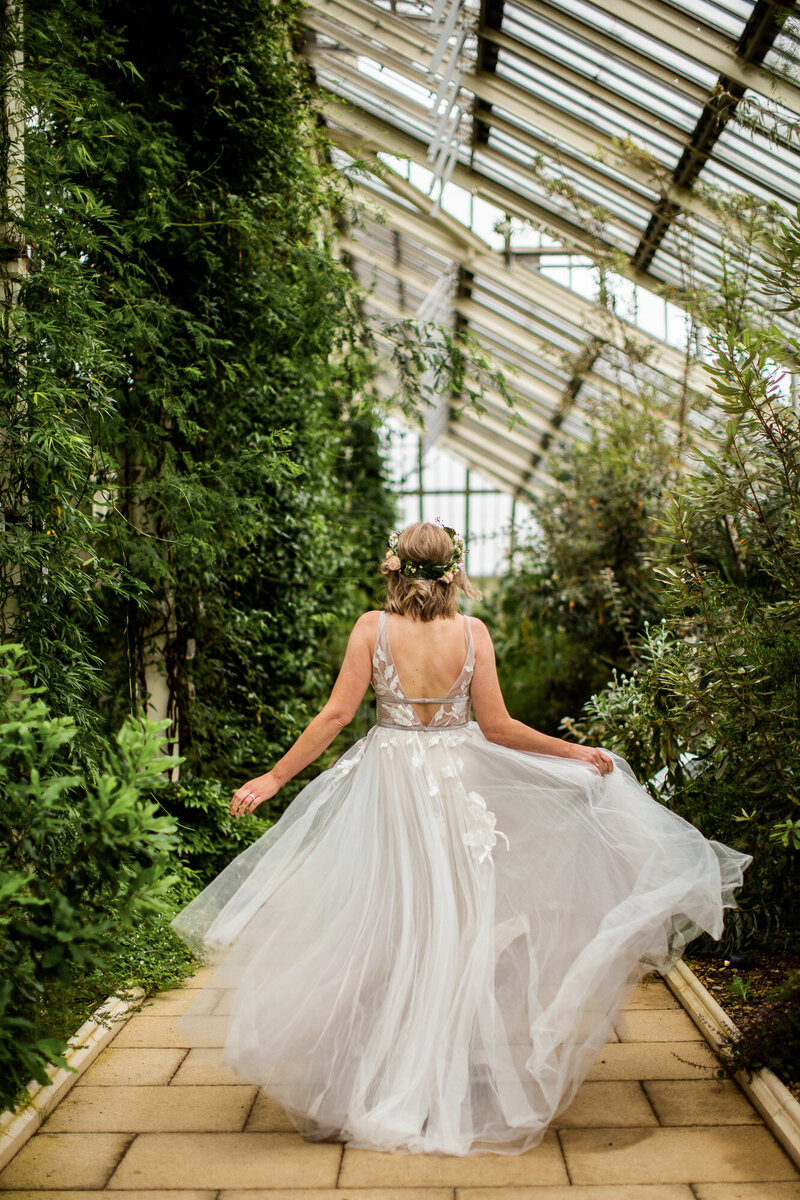 Bride with floaty dress running through greenhouse