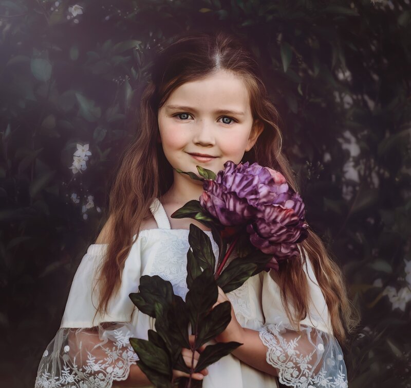 Young girl holds large purple flower