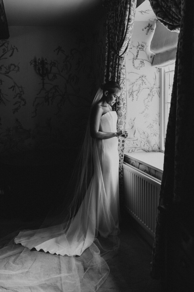 Bride stood in the window of Dewsall Court before getting married