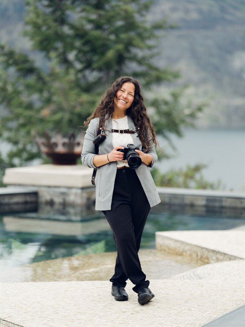 a photographer standing smiling in front of a bridge