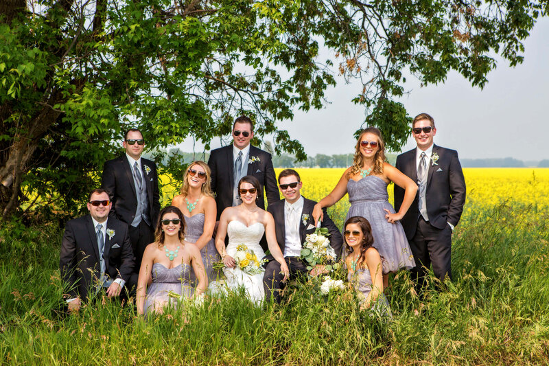 large wedding party wearing sunglasses  sitting in tall  grass
