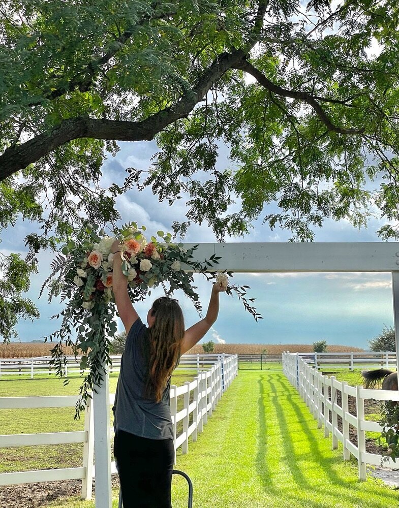 Floral designer creating wedding flower arch at Farm wedding  in will county