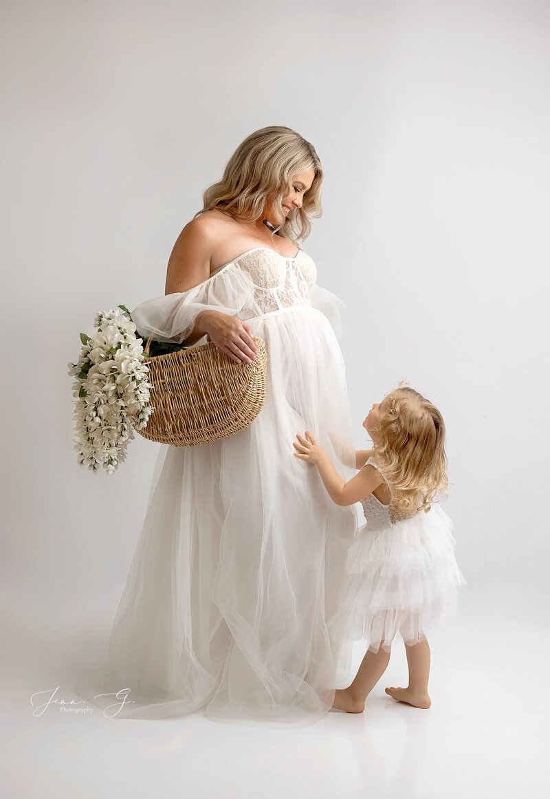 A mother looks down at a happy toddler in a beautiful gown during a photoshoot in coquitlam