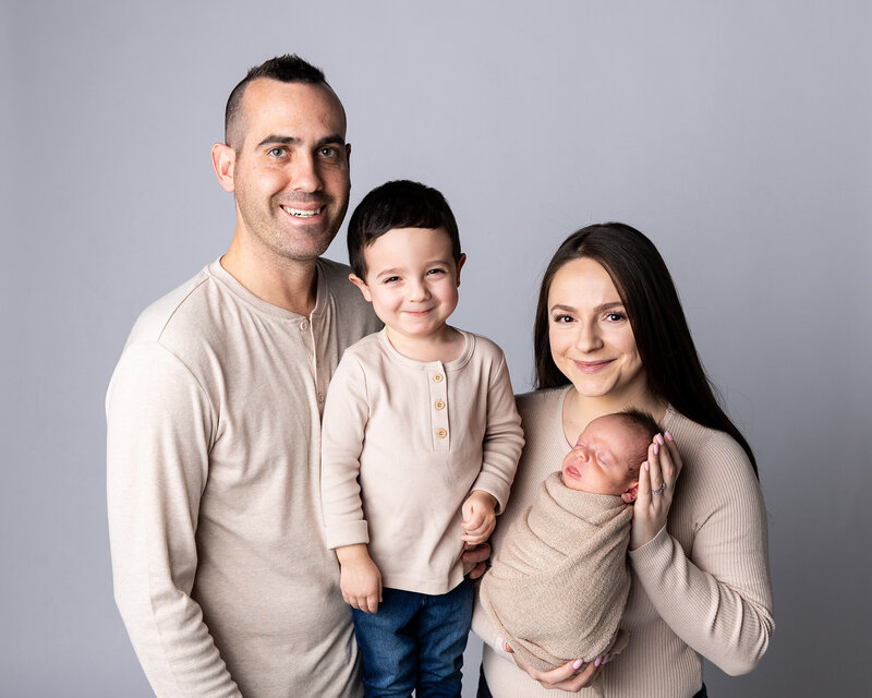 Family of two boys pose for their family newborn session with neutral tones.