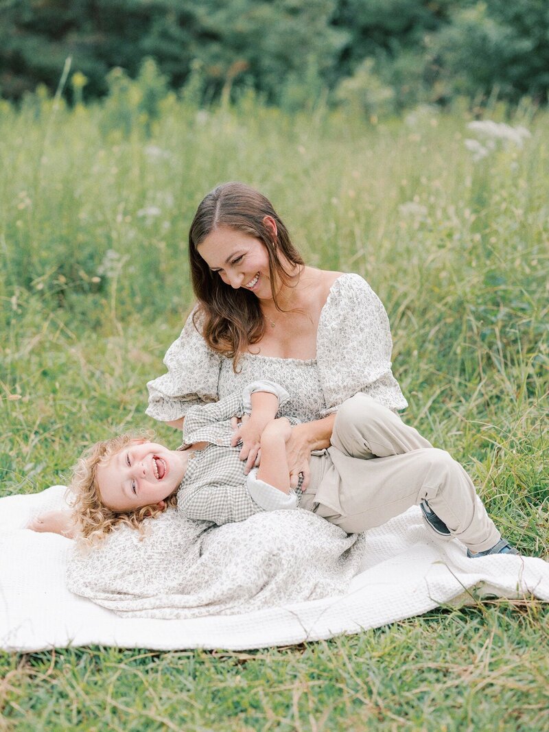 mom-tickling-son-on-blanket