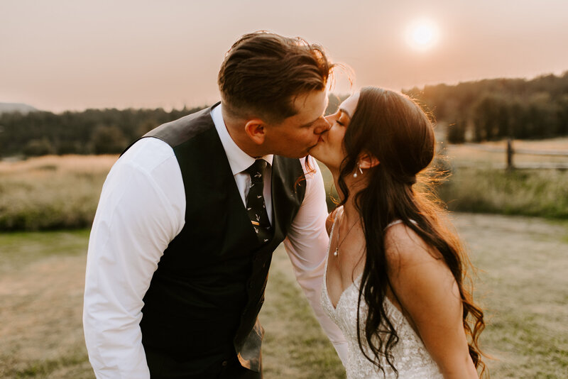 A bride and groom holding hands while walking together on  a rooftop during sunset.
