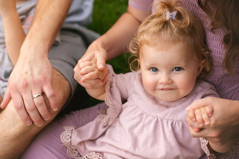 A-happy-baby-smiling-while-holding-mom’s-hands-during-a-family-photo-session-in-Indianapolis-capturing-sweet-bonding-moments