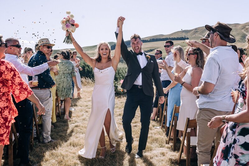 a bride and groom have confetti thrown on them as they exit their wedding ceremony at the boneline vineyard waipara