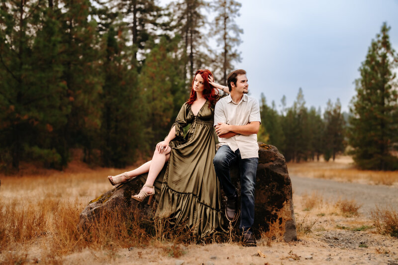 Family Photographer, a man and woman sit beside each other on a rock in the forest