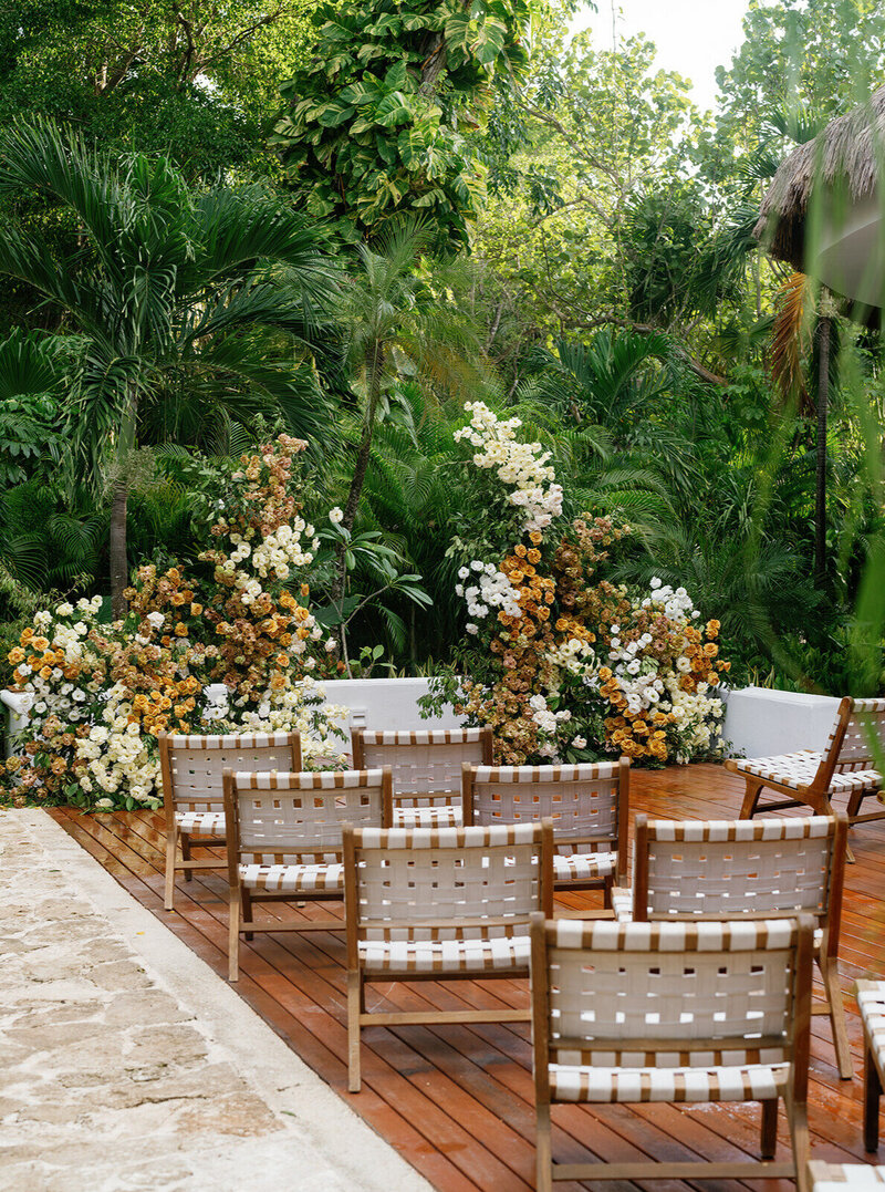 An intimate outdoor wedding setting with lush greenery and a floral arch