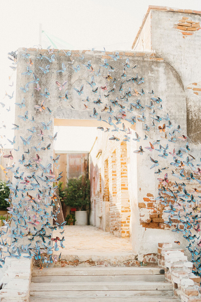 White wood wedding ceremony arbor covered with red and pink flowers