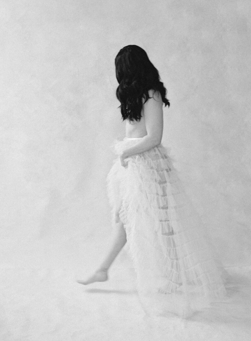 black and white photo of woman walking in just a sheer tulle skit her hair obscures her top showcasing boudoir photographer in seattle Jacqueline Benét 