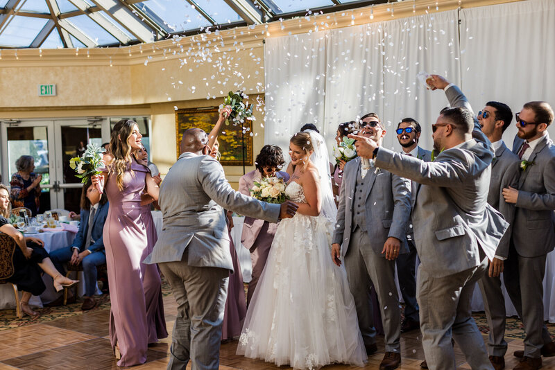 Bridal party celebrating with confetti in the garden atrium at the Ambassador Hotel and Conference Center in Erie, PA