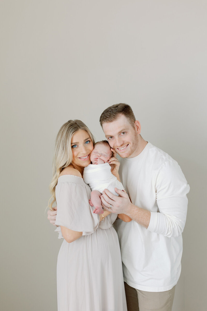 Father and mother cuddle with their newborn.