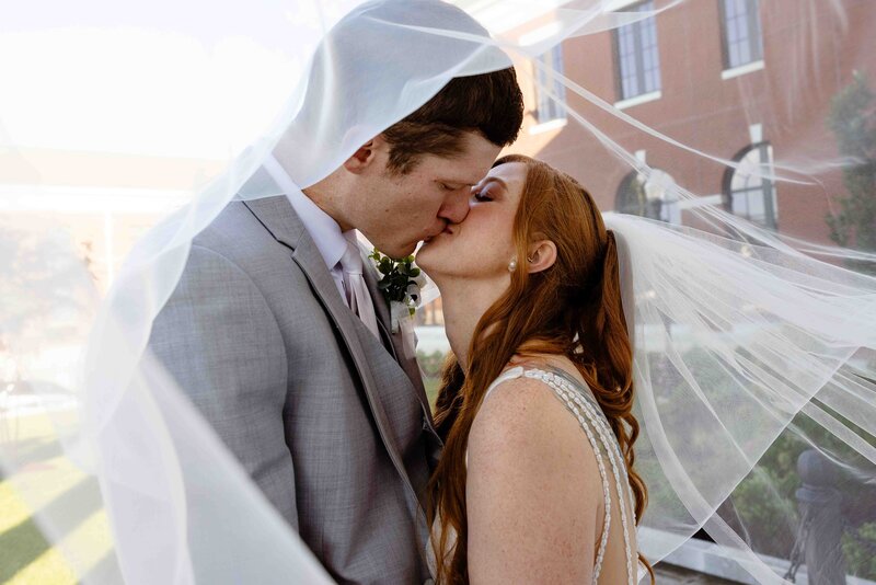 man and woman kissing under bridal veil